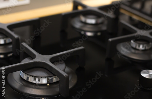 stainless steel gas hob detail on black stone worktop, close-up, matte black stylish four burner, reflective surface