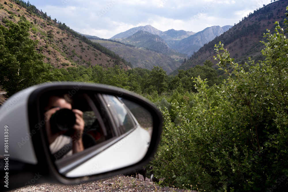 Young woman photographing landscapes near her car on the top of mountain