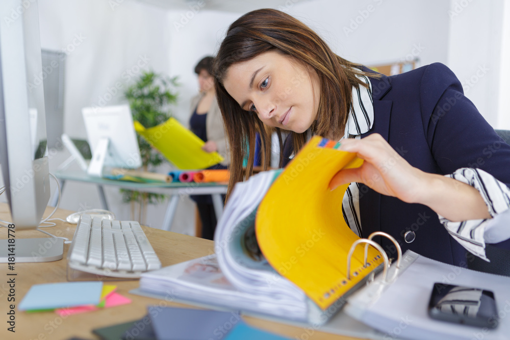 female office worker flicking through paperwork in folder female office worker flicking through paperwork in folder