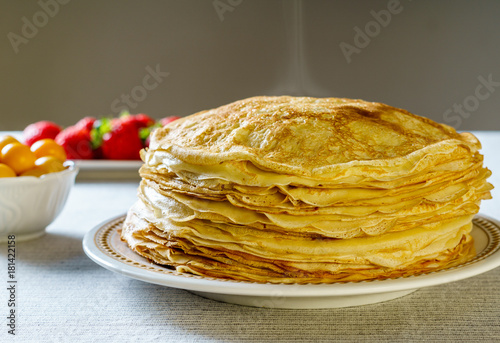 Vászonkép Pile of just made hot Russian pancakes or blini with berries.