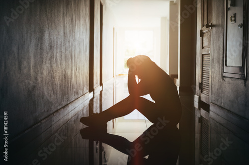 Silhouette of sad and depressed women sitting at walkway of condominium or office with backlit and lens flare,sad mood,feel tired, lonely and unhappy.Vintage style. photo