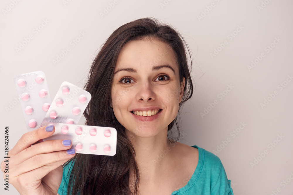 Young woman on a white background holds a pack of pills, pharmaceuticals Young woman on a white background holds a pack of pills, pharmaceuticals
