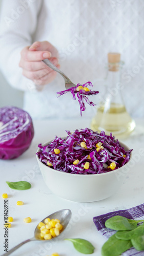 Salad of red cabbage and corn. Woman s hand holds fork with salad