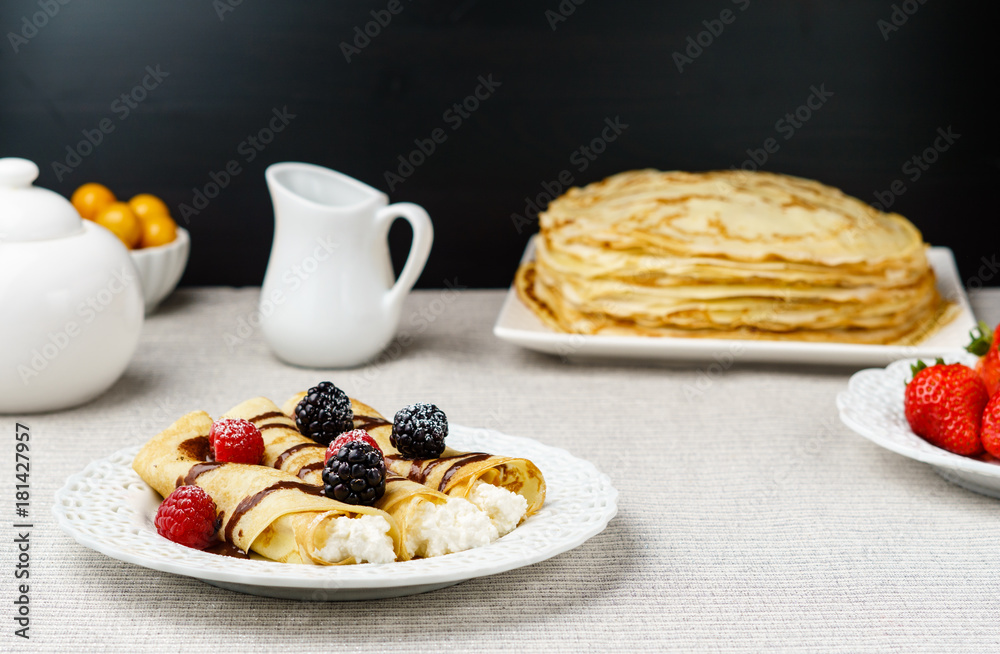 Crepes stuffed with cheese and berry topping on a plate for breakfast.