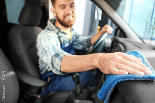 Man cleaning salon with rag in car