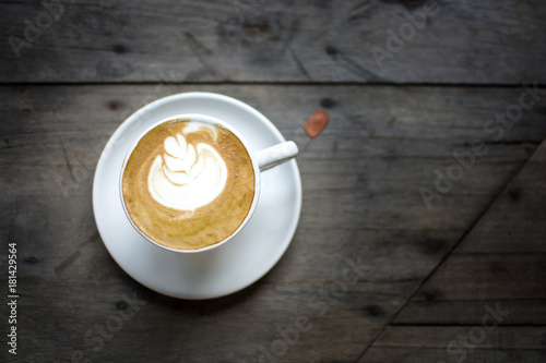 Low key of white cup of hot coffee with the white cream and white plate on the wooden table in the restaurant or coffee shop, cappuccino.