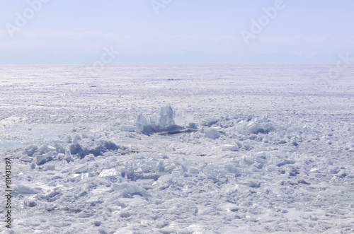 Transparent blue ice hummocks on lake Baikal shore. Siberia winter landscape view. Snow-covered ice of the lake. Big cracks in the ice floe. © anya babii