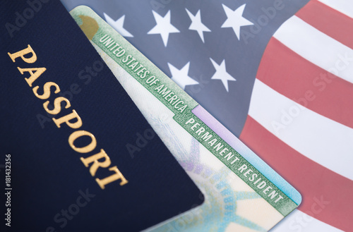Canvas Print United States of America permanent resident card, green card, displayed with a US flag in the background and a passport in the foreground