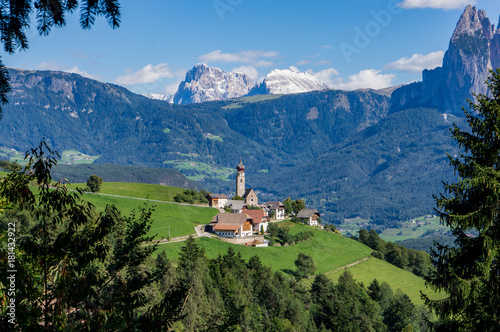 View Alpine village with church and buildings at summer day, Dolomites mountains background.  Soprabolzano, Oberbozen, South Tirol, Italy.