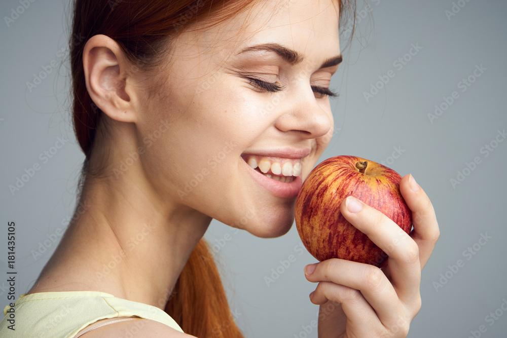 Smile, woman on a gray background holds an apple, fruit, diet, healthy food, health, beauty Smile, woman on a gray background holds an apple, fruit, diet, healthy food, health, beauty