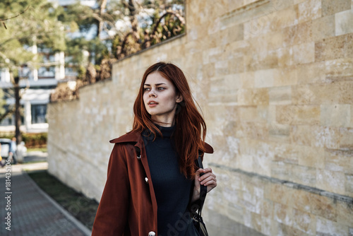 Beautiful young woman with red hair walking outdoors, city