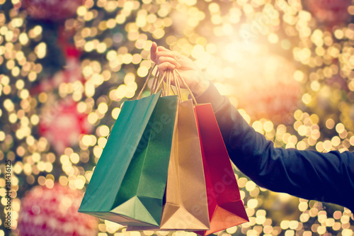Christmas with shopping bags in human hand on christmas decoration and lighting street background photo