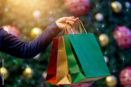 Christmas shopping bags in hand on christmas decoration and light at night on street background