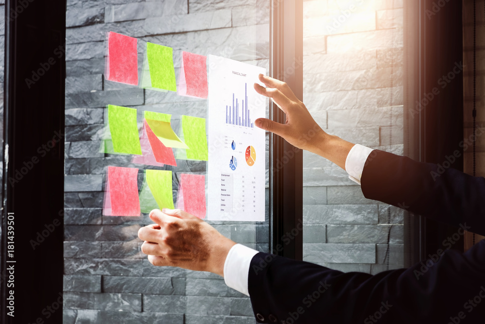 Fototapeta premium Young employees are analyzing the company's expenses using bar graph paper and posting at work his.