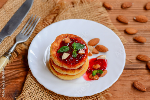 Fried cottage cheese pancakes with berry jam, almonds and mint on a white plate. Syrniki recipe. Low carb cottage cheese pancakes