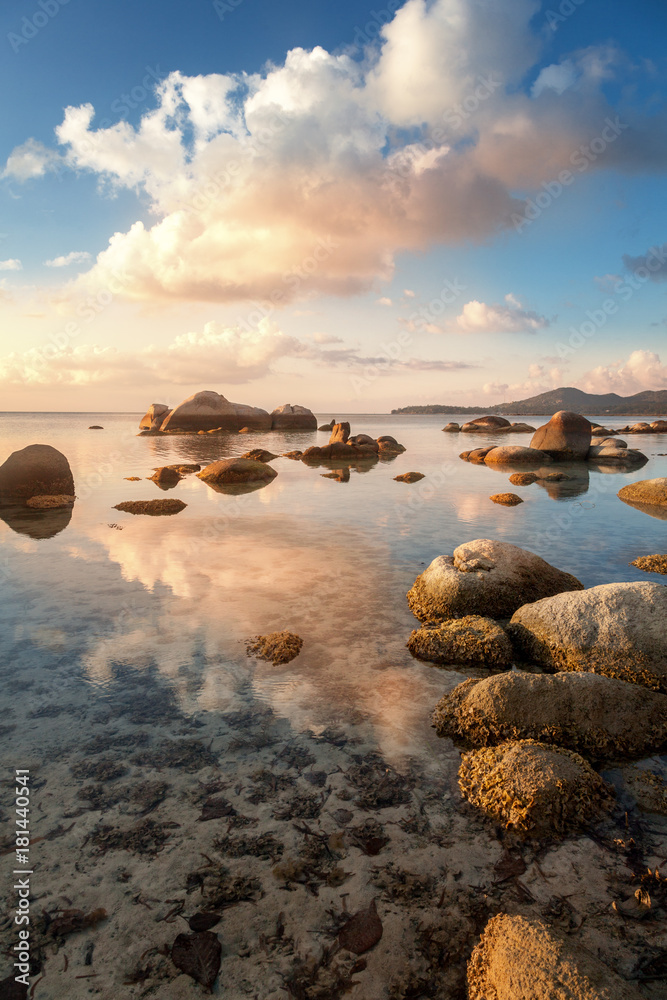Sea shore at sunset with large stones and reflection of clouds in the water. Beautiful tropical landscape Sea shore at sunset with large stones and reflection of clouds in the water. Beautiful tropical landscape
