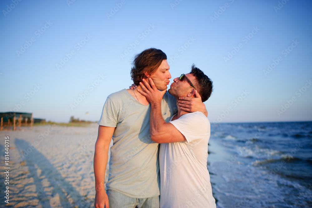 Two men embrace against the background of the sea.