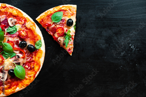 Pizza slice with Pepperoni, melting cheese and olives served at a pizzeria or restaurant