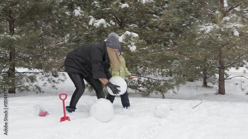 Mom and son make a snowman 2 Happy mother and son make a snowman falling fluffy snow