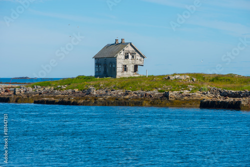 Scenic rocky coastline of island Rost in Norway with houses and old lighthouse