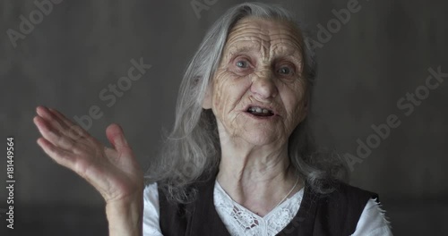 Portrait of old woman with grey hair telling story and gesticulating hands.