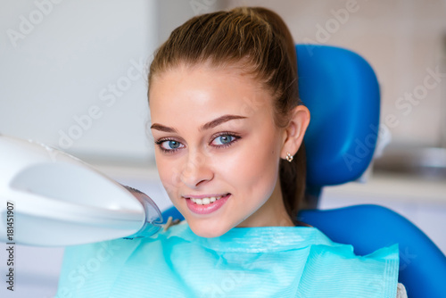 Beautiful girl whitens teeth in dentistry.