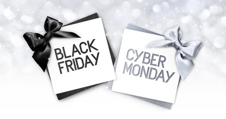 black friday and cyberg monday text write on gift card label with black and silver ribbon bow on blurred bright lights background