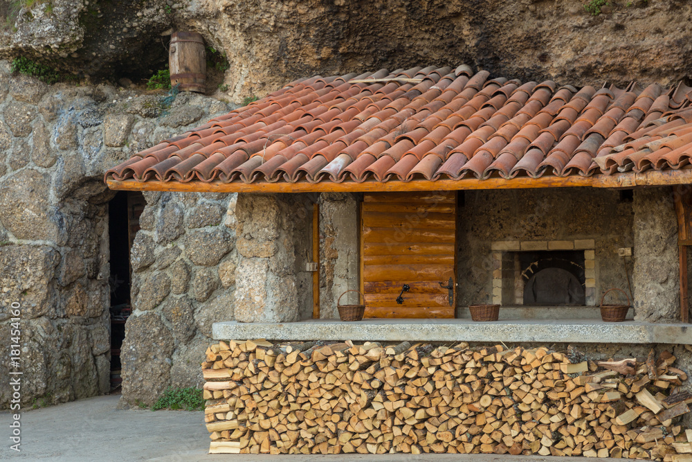 entrance to old stone wall,  veranda with  red tiled roof and firewood