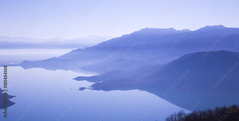 mountains reflected in  water in blue light of  morning
