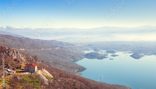 house with  red roof on  hill on  background of blue water and  mountain range in  haze © Aleksei Lazukov