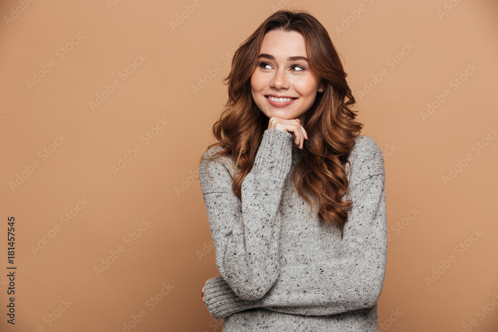 Young attractive woman in woolen sweater holding her chin, looking aside Young attractive woman in woolen sweater holding her chin, looking aside