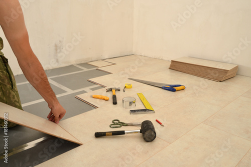 Carpenter worker installing wood parquet board during flooring work