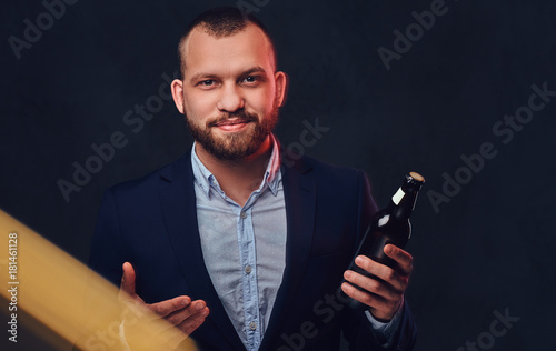 A man dressed in an elegant suit holds craft beer.