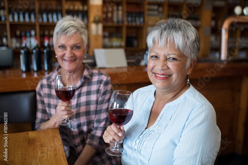 Two female senior friends having red wine in restaurant