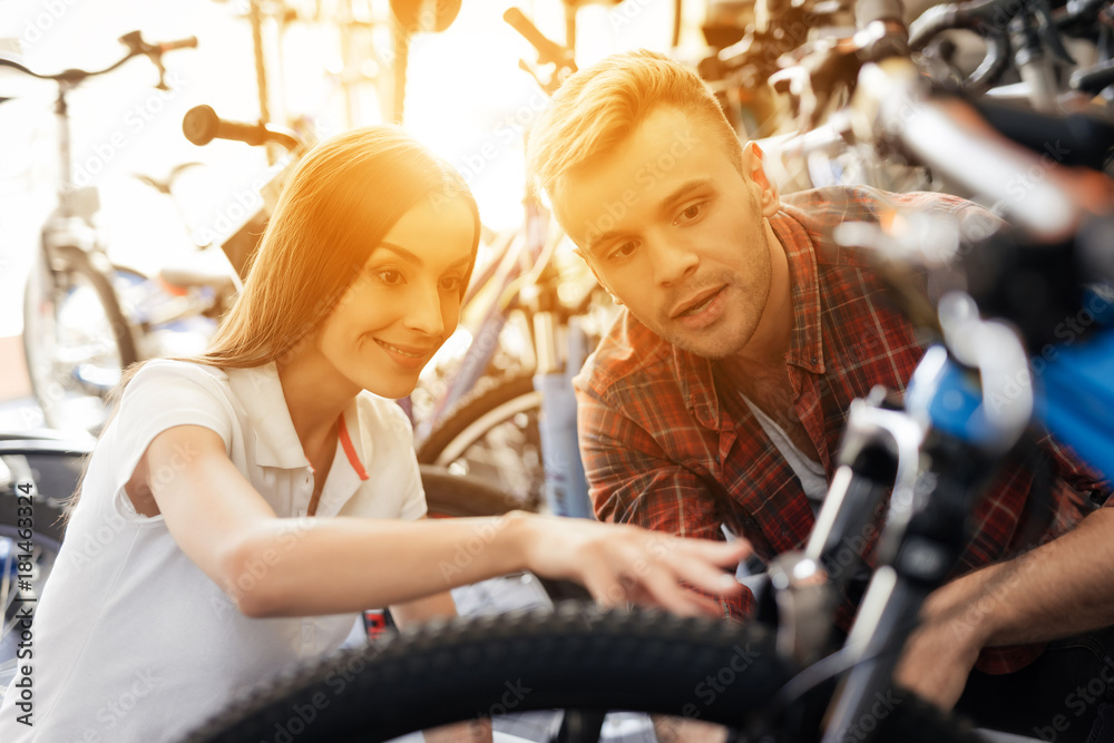 A girl consultant shows the buyer in a bicycle store.