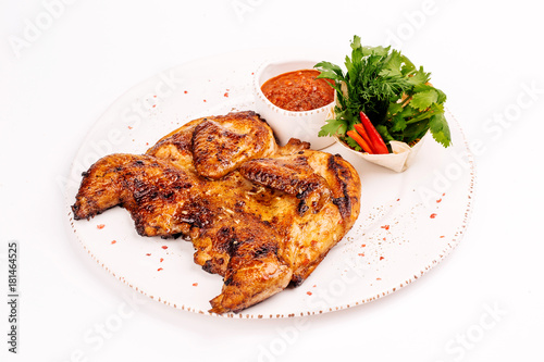 Grilled chicken Tabaka with sauce on a plate on white background for menus.