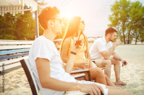 Young people enjoying summer vacation sunbathing drinking at beach bar