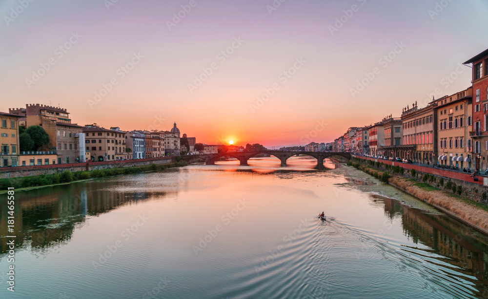 Sunset time in Florence, Italy. Bright sky over Arno river and medieval bridge.