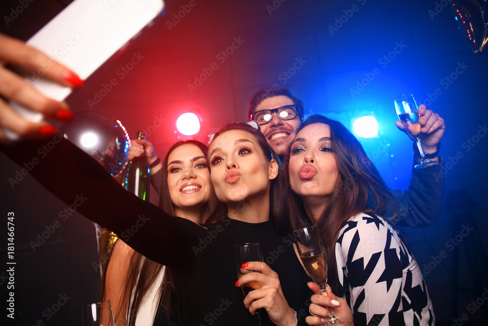 party, technology, nightlife and people concept - smiling friends with  smartphone taking selfie in club. Stock Photo