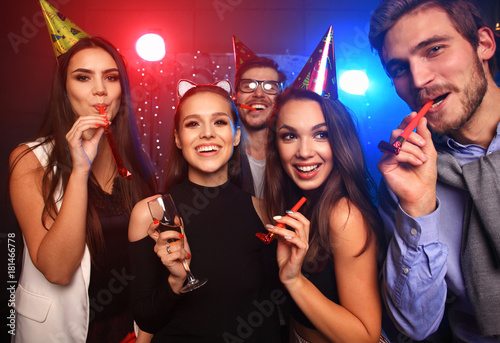 Friends making big party in the night. Five people throwing confetti and drinking champagne.