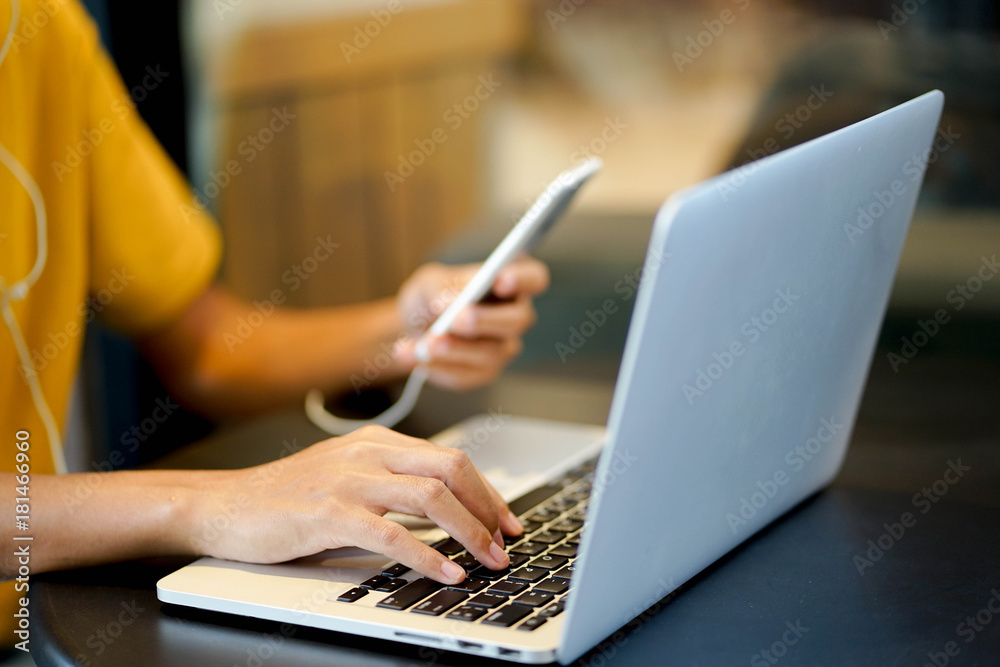 close up young girl hand typing o keyboard laptop while playing smartphone at coffee cafe shop , life style concept close up young girl hand typing o keyboard laptop while playing smartphone at coffee cafe shop , life style concept