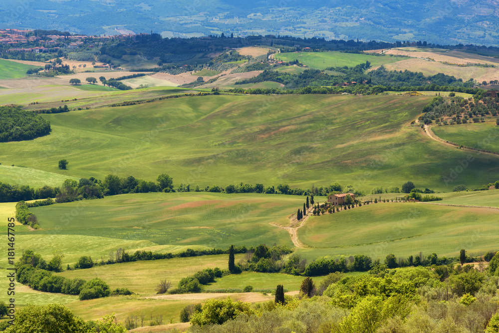 Magnificent spring landscape.Beautiful view of typical tuscan farm house, green wave hills, cypresses trees, hay bales, olive trees, beautiful golden fields and meadows.Tuscany, Italy, Europe
