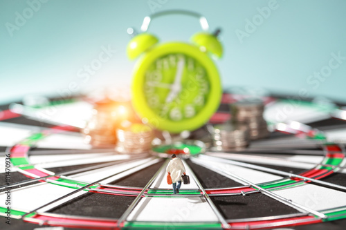 Miniature people: businessman running on dart board and try to race against time and beat the clock to be a winner (Financial and Business competition concept)