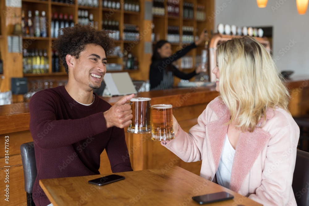 Couple toasting glass of beer in bar
