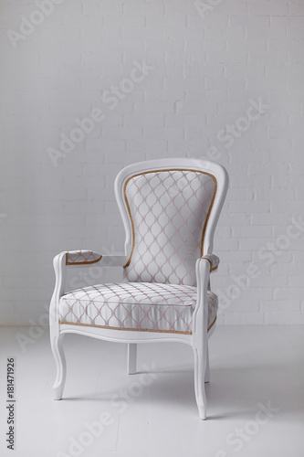 Elegant white armchair on white wall background