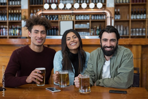 Smiling friends having glass of beer in bar