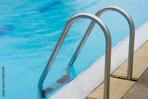 Grab bars ladder in the blue swimming pool © Suphansa