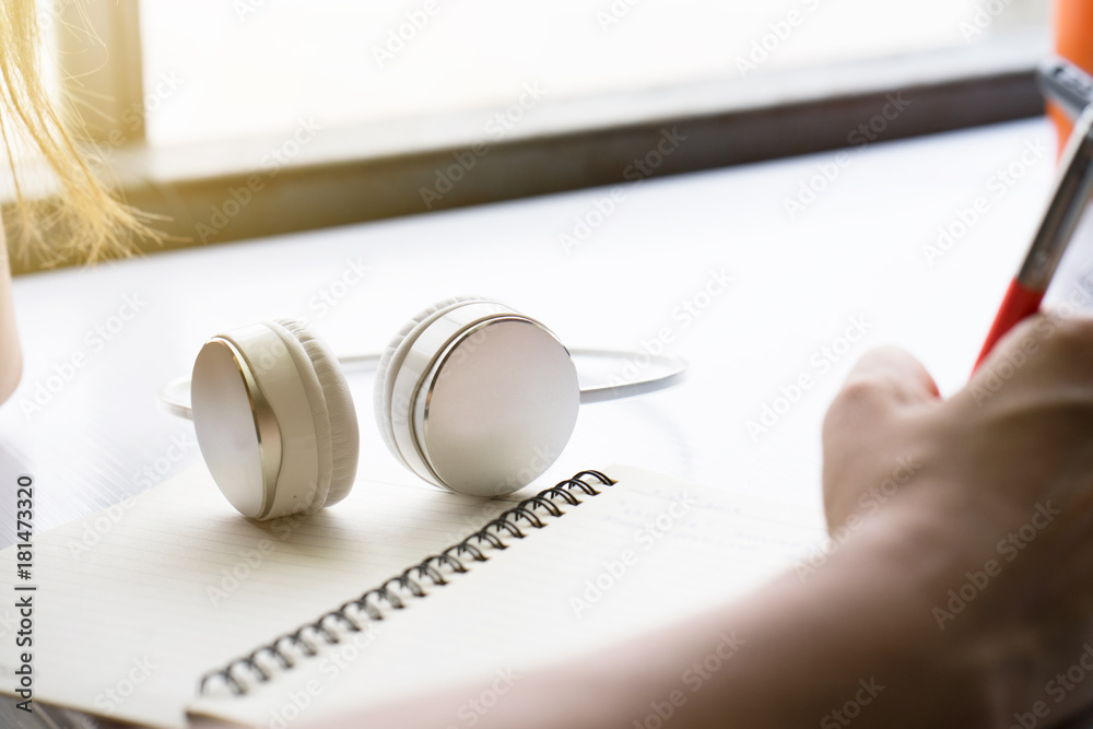 Hand hold pen on book for write text near smart phone and white headphones. Hand hold pen on book for write text near smart phone and white headphones.