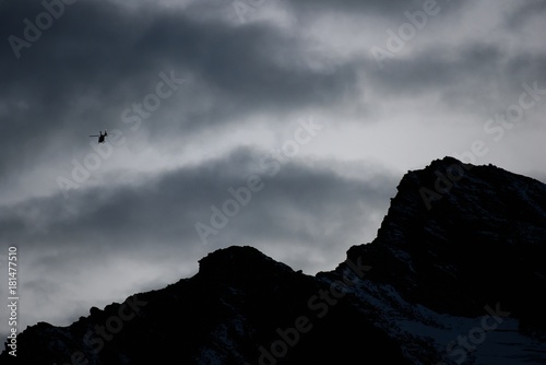 Rescue helicopter fly in Swiss Alps at sunset