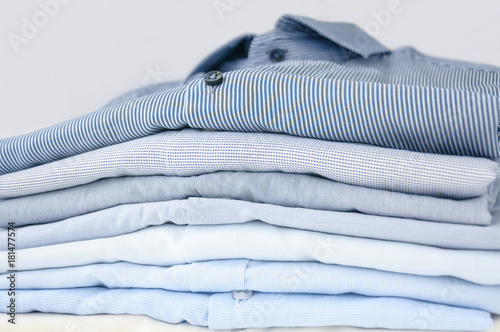 Neatly folded men's shirts of pastel tones. Close-up with soft focus